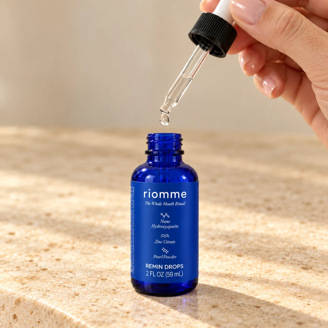 A hand lifting the dropper from a bottle of Remin Drops