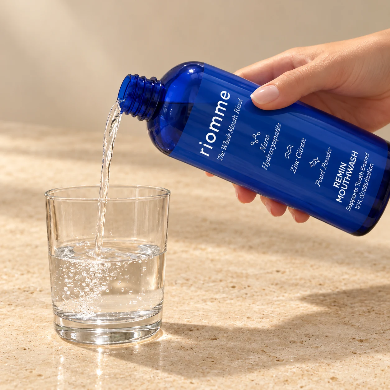 A hand pouring Remin Mouthwash into a glass