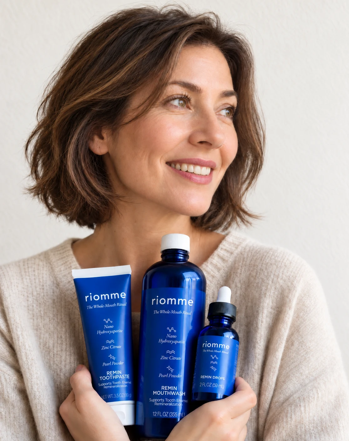A woman holding Remin Toothpaste, Remin Mouthwash and Remin Drops close to her chest